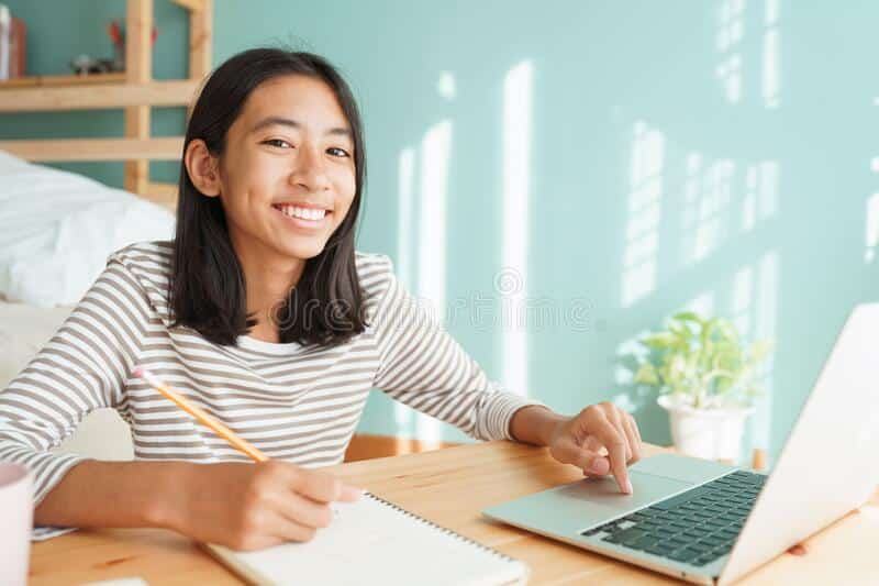 asian girl learning online via internet tutor laptop computer asia child studying sitting interior home