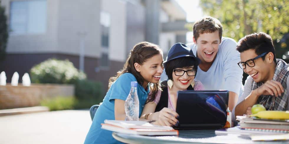 students using laptop together outdoors royalty free image